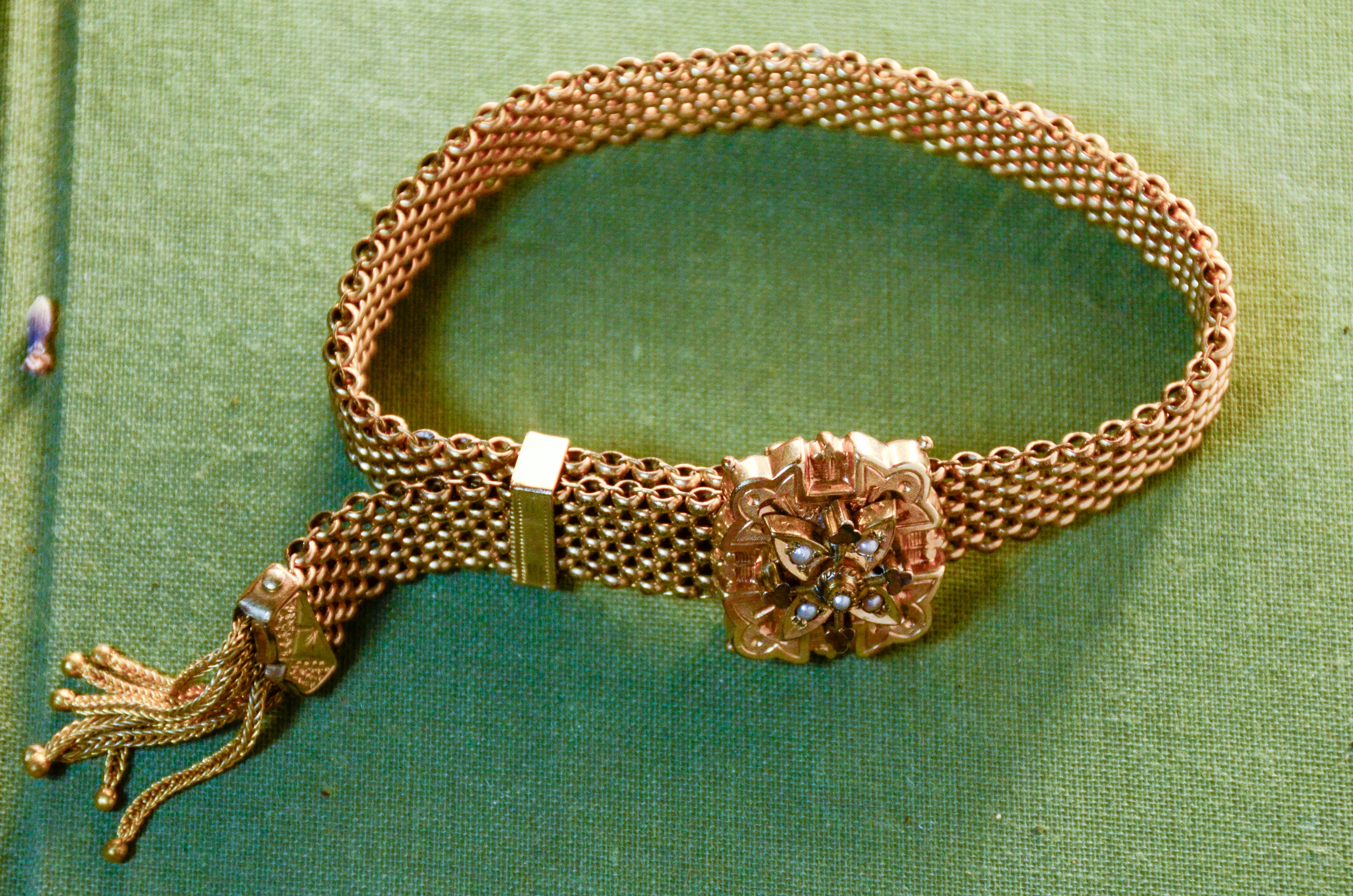 Gold mesh bracelet with decorative clasp on a green background