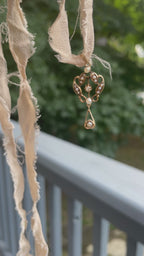 A gold lavalier pendant with seed pearls and a center diamond swaying on a beige silk ribbon.